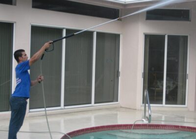 A man is cleaning the pool with a hose.
