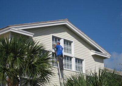 A man on a ladder cleaning the outside of a house.