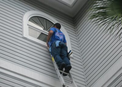 A man on a ladder cleaning the outside of a house.