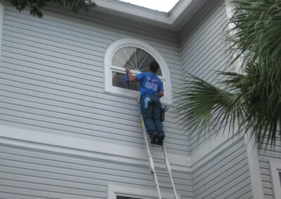 A man on a ladder cleaning the outside of a house.