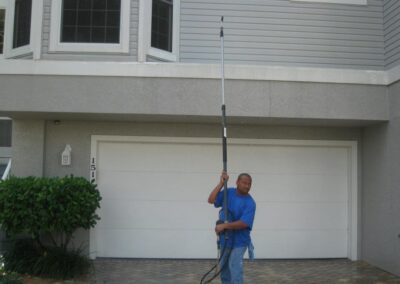 A man holding a pole in front of a house.