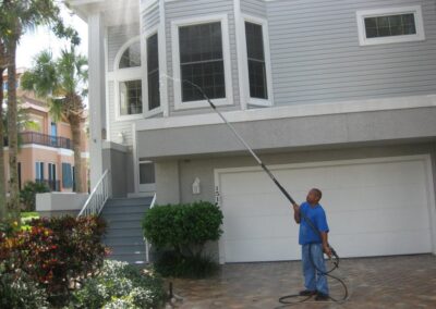 A man in blue shirt holding hose near house.