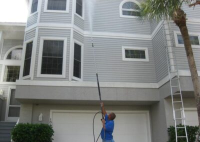 A man holding a hose and a pole outside of a house.