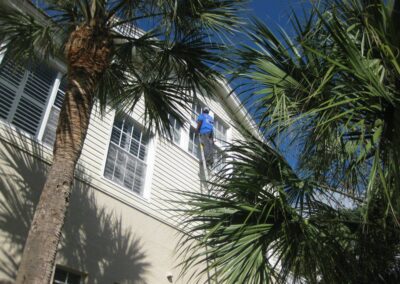 A man is on the side of a building while hanging from a ladder.